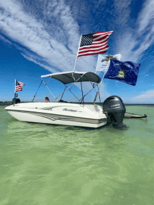 Boat with colorful flags flying against a backdrop of the ocean and a clear blue sky, representing the ultimate boat charter experience in Islamorada with Island Adventures. Boat with colorful flags sailing under a clear blue sky, showcasing the best Boat Charter in Islamorada with Island Adventures.